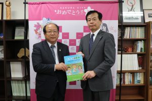 橋本教育長(右)に教材を手渡す長嶋専務